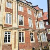 Teilansicht der Rückseite vom Erbdrostenhof Münster. Ziegelsteinbauweise mit Sandsteineinrahmungen der weißen Sprossenfenster.