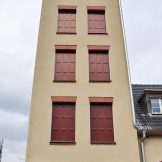 Turm des Feuerwehrhauses mit sechs mit Holzverkleidung verschlossenen Fenstern, Kassettenoptik in Dunkelrot